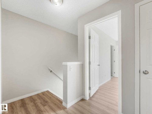 Hallway with light wood-finish flooring, white trim, and a white ceiling-mounted light fixture - 17 15128 22 Street, Edmonton, AB - Indoor Photo Showing Other Room