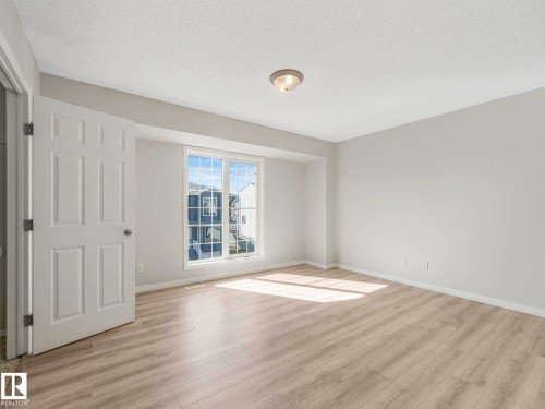 Room featuring light wood-finish flooring, a multi-pane window, white baseboards, and a flush-mount ceiling light - 17 15128 22 Street, Edmonton, AB - Indoor Photo Showing Other Room