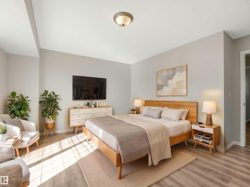 Spacious bedroom featuring light-toned walls, wood-finish flooring, a contemporary ceiling light fixture, and a neutral color palette - 17 15128 22 Street, Edmonton, AB - Indoor Photo Showing Bedroom
