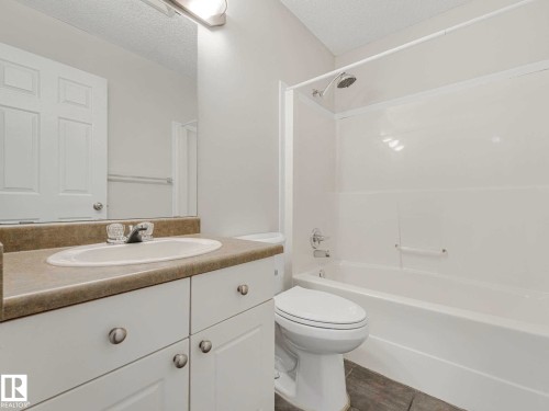 Bathroom featuring a vanity with a laminate countertop, an undermount sink, and a white cabinet base - 17 15128 22 Street, Edmonton, AB - Indoor Photo Showing Bathroom