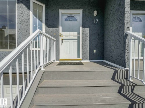 Entryway featuring textured gray stucco siding, white trim, and a white storm door - 17 15128 22 Street, Edmonton, AB - Outdoor With Exterior