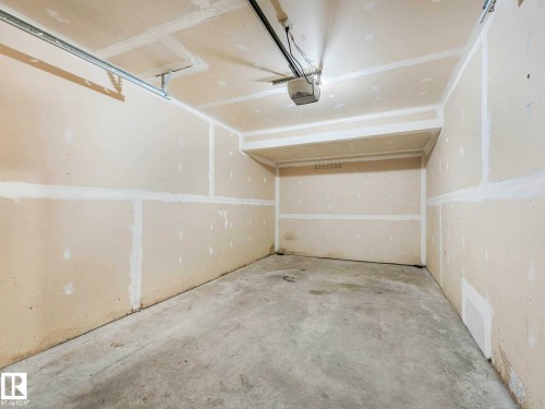 Unfinished garage space featuring gypsum board walls, a concrete floor, and an overhead garage door opener mechanism - 17 15128 22 Street, Edmonton, AB - Indoor Photo Showing Garage