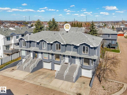 Three-story multi-unit property featuring a neutral gray exterior, individual garage doors, and private front entrances with stairs - 17 15128 22 Street, Edmonton, AB - Outdoor