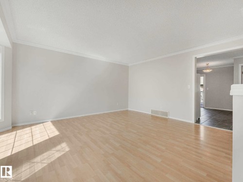 Spacious interior featuring light wood-finish flooring, white baseboards, and white crown molding - 17 15128 22 Street, Edmonton, AB - Indoor Photo Showing Other Room