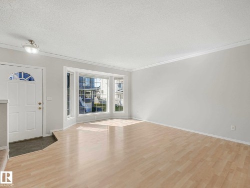 Spacious entry area with wood-finish flooring, a white front door with an arched transom, and a bay window - 17 15128 22 Street, Edmonton, AB - Indoor Photo Showing Other Room