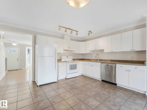 Kitchen featuring white cabinetry, tile flooring, and a stainless steel dishwasher - 17 15128 22 Street, Edmonton, AB - Indoor Photo Showing Kitchen