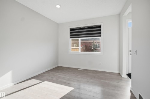 This bright room features light-colored flooring, a window with horizontal blinds, and a recessed ceiling light - 2125 Maple Road Nw, Edmonton, AB - Indoor Photo Showing Other Room