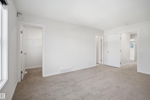 Spacious room featuring light-colored carpet flooring, white walls, and a window with a white frame - 2125 Maple Road Nw, Edmonton, AB - Indoor Photo Showing Other Room