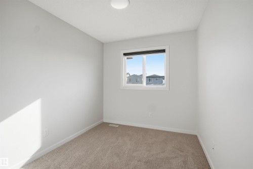 The room features neutral-toned carpet, light gray walls, and a window with a black frame - 2125 Maple Road Nw, Edmonton, AB - Indoor Photo Showing Other Room