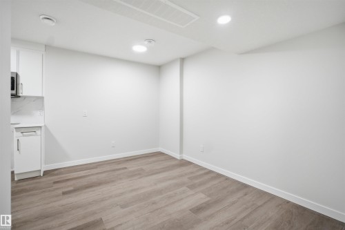 This bright interior space features light-colored walls and wood-style flooring, complemented by white baseboards - 2125 Maple Road Nw, Edmonton, AB - Indoor Photo Showing Other Room