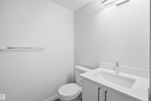 This bathroom features a contemporary vanity with a white countertop and a chrome faucet, a white toilet, and a towel bar mounted on a white wall - 2125 Maple Road Nw, Edmonton, AB - Indoor Photo Showing Bathroom