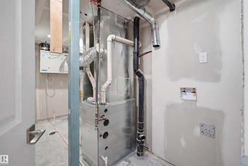 Utility area featuring a furnace, various pipes, and a white electrical outlet - 2125 Maple Road Nw, Edmonton, AB - Indoor