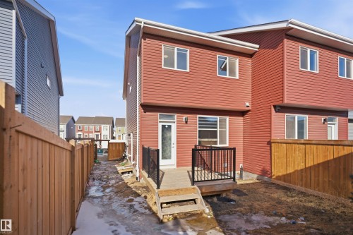 The property features a red exterior with white trim, a rear door providing exterior access, and a deck with black railings - 2125 Maple Road Nw, Edmonton, AB - Outdoor With Exterior