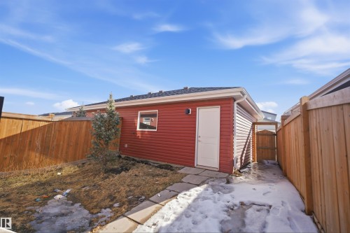 The property includes an exterior building with red siding, a white door, and a small window, set within a fenced yard - 2125 Maple Road Nw, Edmonton, AB - Outdoor With Exterior