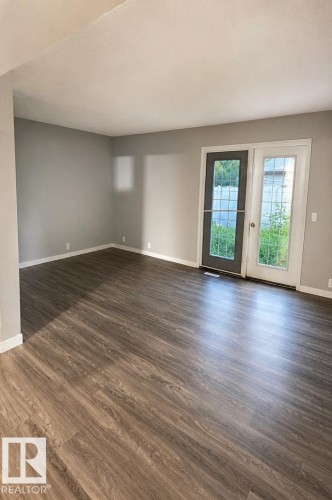 Wood-finish flooring throughout, dual French doors with glass panels, and light gray wall color - 14075 30 Street Nw, Edmonton, AB - Indoor Photo Showing Other Room