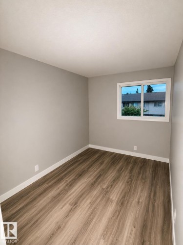 Wood-finish flooring with crisp white trim - 14075 30 Street Nw, Edmonton, AB - Indoor Photo Showing Other Room