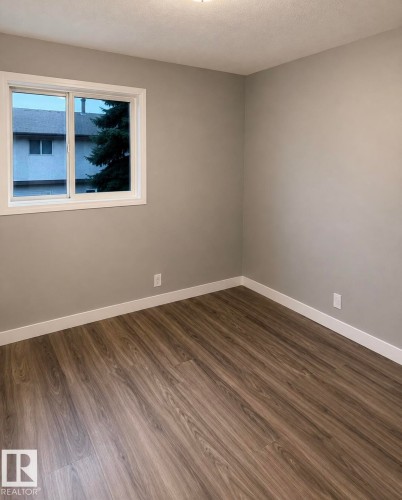 Wood-finish flooring, neutral wall tones, white trim, and a window with white casing - 14075 30 Street Nw, Edmonton, AB - Indoor Photo Showing Other Room