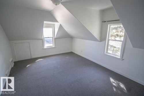 Attic space featuring dormer windows, grey carpeting, sloped ceilings, and a built-in storage access panel - 4814 51 Ave, St. Paul Town, AB - Indoor Photo Showing Other Room