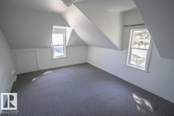 Attic space featuring dormer windows, grey carpeting, sloped ceilings, and a built-in storage access panel - 