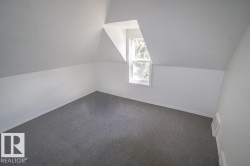 Room featuring a dormer window, neutral wall paint, white trim, and gray carpeting - 