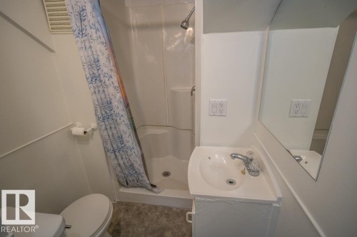 Compact bathroom featuring a shower stall, white pedestal sink, built-in mirror, and white toilet - 4814 51 Ave, St. Paul Town, AB - Indoor Photo Showing Bathroom