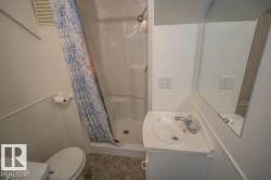 Compact bathroom featuring a shower stall, white pedestal sink, built-in mirror, and white toilet - 