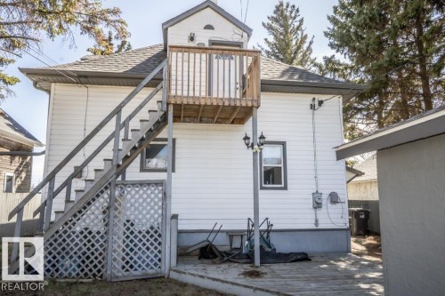 Rear exterior featuring white horizontal siding, a gabled roofline, and a second-story wooden deck with stairs descending to a ground-level deck - 4814 51 Ave, St. Paul Town, AB - Outdoor With Exterior