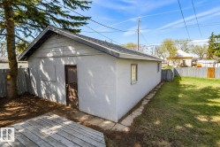 Detached garage with white stucco exterior, grey shingle roof, and a single window - 