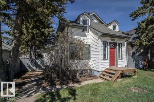White siding exterior with a contrasting red front door, featuring a wood deck entry with stairs - 4814 51 Ave, St. Paul Town, AB - Outdoor