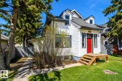 White siding exterior with a bright red entry door and a wood-finish deck - 