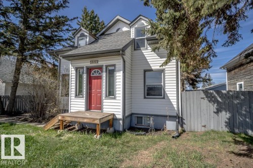 White siding exterior with a vibrant red entry door featuring an arched window - 4814 51 Ave, St. Paul Town, AB - Outdoor