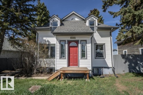 White siding exterior featuring a prominent red entry door with an arched window - 4814 51 Ave, St. Paul Town, AB - Outdoor