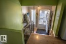 Entryway featuring wood-finish flooring, a white paneled entry door, and a black wrought iron staircase railing with a wood handrail - 4814 51 Ave, St. Paul Town, AB  - Indoor Photo Showing Other Room 