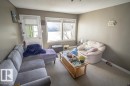 Carpeted living space featuring neutral wall tones, a large window, and a white door with glass paneling - 4814 51 Ave, St. Paul Town, AB  - Indoor Photo Showing Living Room 