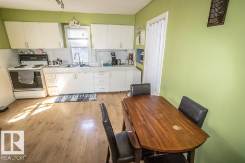 Kitchen with wood-finish flooring, white cabinetry, and a white tile-look backsplash - 4814 51 Ave, St. Paul Town, AB - Indoor Photo Showing Kitchen