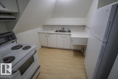 Kitchenette featuring a white electric range, white refrigerator, and light wood-finish flooring - 4814 51 Ave, St. Paul Town, AB - Indoor