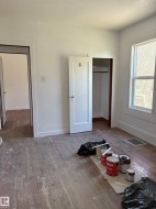Room featuring wood-finish flooring, white walls, and a window with white trim - 