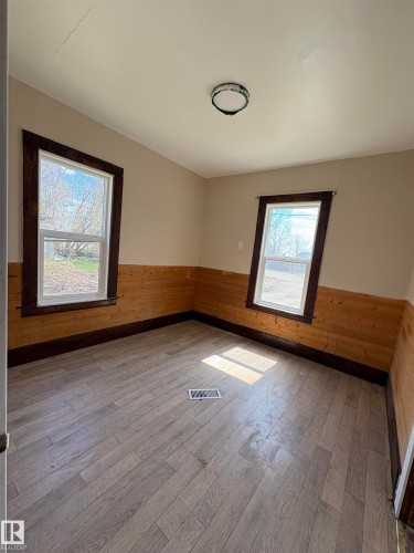 Room featuring half-height wood paneling, and two windows with dark trim. - 4622 50 Avenue, Elk Point, AB - Indoor Photo Showing Other Room