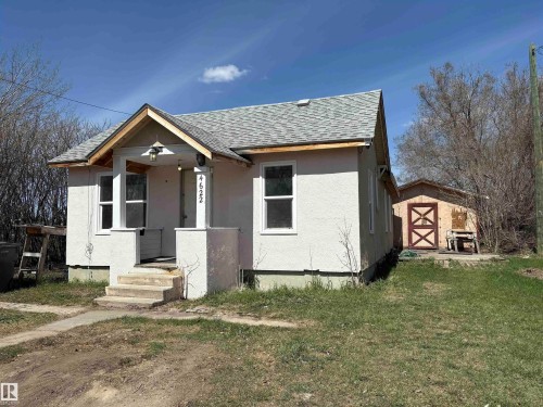 Stucco-finish exterior with a gabled entry porch featuring two square columns and an overhead light fixture. - 4622 50 Avenue, Elk Point, AB - Outdoor