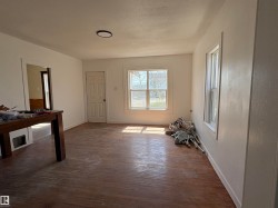 Enter into the spacious living room. Bright interior space featuring wood-finish flooring, white walls, and multiple windows. - 