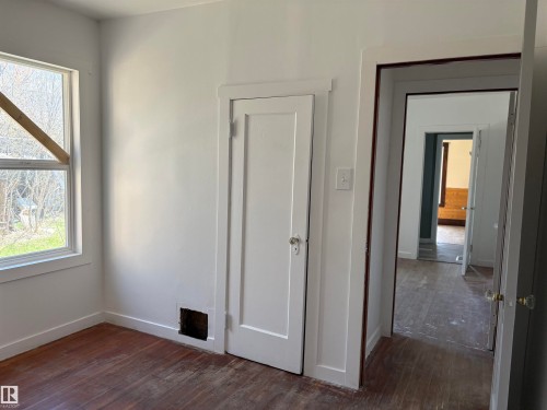 Interior space featuring a window, white walls, and wood-finish flooring - 4622 50 Avenue, Elk Point, AB - Indoor Photo Showing Other Room
