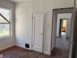Interior space featuring a window, white walls, and wood-finish flooring - 