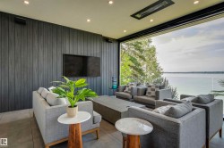 Expansive indoor-outdoor living area featuring floor-to-ceiling glass, a built-in television, recessed ceiling lighting, and wood-finish wall paneling - 