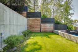 Lush lawn area bordered by a concrete retaining wall and tiered timber fencing - 