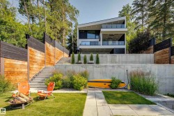 Modern multi-level residence featuring an angular roofline, two balconies with glass railings, and expansive windows - 