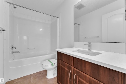 Bathroom featuring a wood-finish vanity with a single basin, a white countertop, and a chrome faucet - 2143 32 Street, Edmonton, AB - Indoor Photo Showing Bathroom