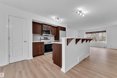Kitchen featuring dark wood cabinetry, stainless steel appliances, and a light-toned backsplash - 2143 32 Street, Edmonton, AB - Indoor Photo Showing Kitchen