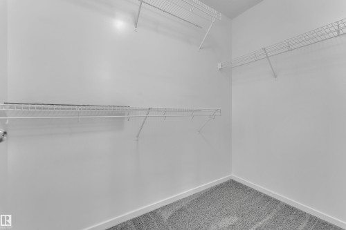 Walk-in closet featuring wire shelving, wire hanging rods, neutral wall paint, and grey carpet flooring - 2143 32 Street, Edmonton, AB - Indoor With Storage