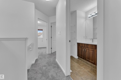 Hallway bathroom featuring a wood-finish vanity with a white countertop, chrome faucet, mirrored medicine cabinet, and tile flooring - 2143 32 Street, Edmonton, AB - Indoor Photo Showing Other Room