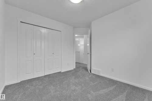 Bedroom featuring light gray carpeting, white walls, white trim, and a white bi-fold closet - 2143 32 Street, Edmonton, AB - Indoor